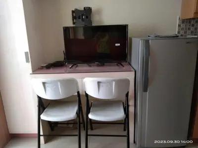 a desk with three chairs and a refrigerator at Shell Residences C19 Shortwalk Sm Mall Of Asia Airport in Manila