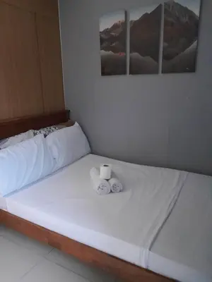 a white bed with two rolls of towels on it at Shell Residences C19 Shortwalk Sm Mall Of Asia Airport in Manila