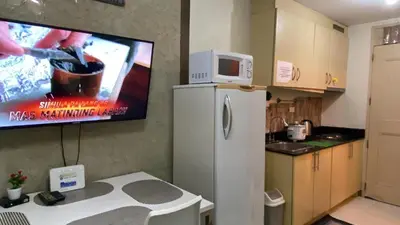 a kitchen with a refrigerator and a tv on the wall at CHATEAU ELYSEE A16 Near Resto And Sm Mall/Airport in Manila