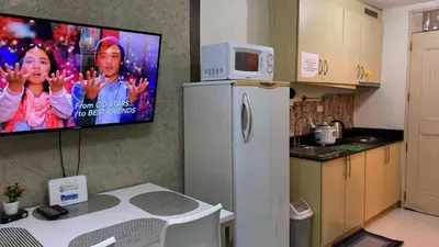 a kitchen with a refrigerator with a tv on the wall at CHATEAU ELYSEE A16 Near Resto And Sm Mall/Airport in Manila