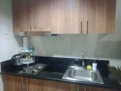 a kitchen counter with a sink and wooden cabinets at 1Bedroom Cozy Condo near MOA in Manila