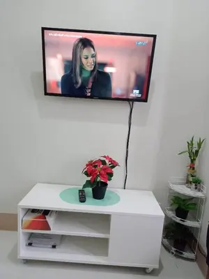 a flat screen tv on a wall with a white table at 1Bedroom Cozy Condo near MOA in Manila