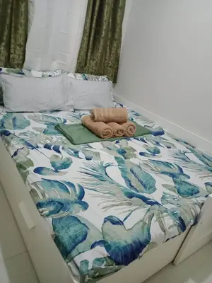a bed with a blue and white comforter on it at 1Bedroom Cozy Condo near MOA in Manila