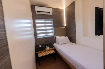 a small room with a bed and a window at Kabayan Hotel Pasay in Manila
