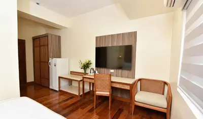 a room with a desk and a tv and a refrigerator at Kabayan Hotel Pasay in Manila