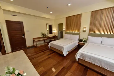 a hotel room with two beds and a table at Kabayan Hotel Pasay in Manila