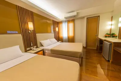 a hotel room with two beds and a television at Kabayan Hotel Pasay in Manila