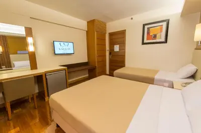 a hotel room with two beds and a desk at Kabayan Hotel Pasay in Manila