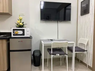 a small kitchen with a table and a tv on the wall at SHORE RESIDENCE D17 shortwalk Mall of asia near airport in Manila