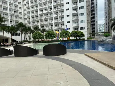 a large building with a swimming pool in front of a building at SHORE RESIDENCE D17 shortwalk Mall of asia near airport in Manila