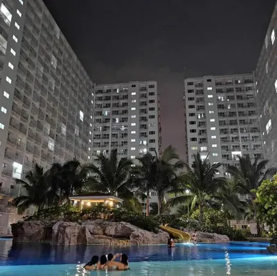 a swimming pool in a city at night with buildings at SHORE RESIDENCE D17 shortwalk Mall of asia near airport in Manila