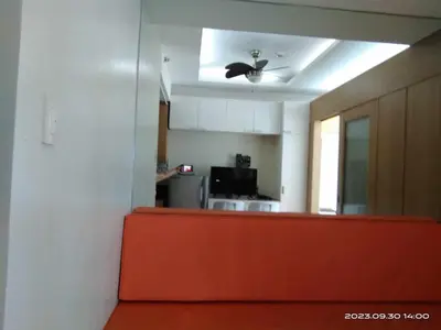 a living room with an orange couch and a kitchen at Shell Residences C21 Shortwalk Sm Mall Of Asia Airport in Manila