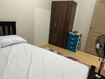 a bedroom with a white bed and a brown cabinet at B-G Sorento Oasis 2BR in Manila