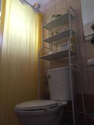 a bathroom with a toilet with aige shower curtain at Arcobaleno in Manila