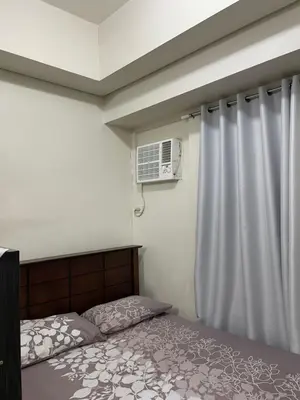 a bedroom with a bed and an air conditioner at Makati Cozy Studio Apartment in Manila