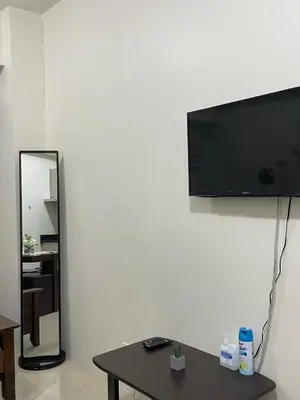a living room with a table and a flat screen tv on a wall at Makati Cozy Studio Apartment in Manila