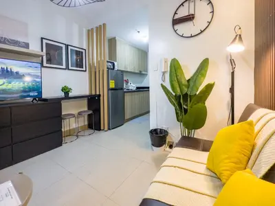 a living room with a couch and a clock on the wall at GemstoneBR in SMDC Shore 2 Residences in Manila