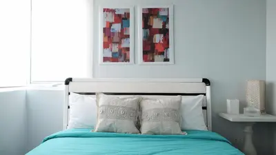 a bed with two pillows and a picture on the wall at One bedroom budget condo in BGC in Manila
