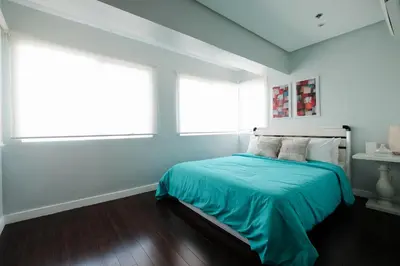 a white bedroom with a bed with a blue blanket at One bedroom budget condo in BGC in Manila