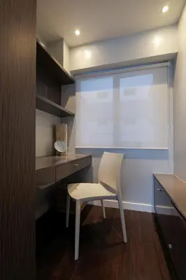 a white chair sitting in front of a desk with a window at One bedroom budget condo in BGC in Manila