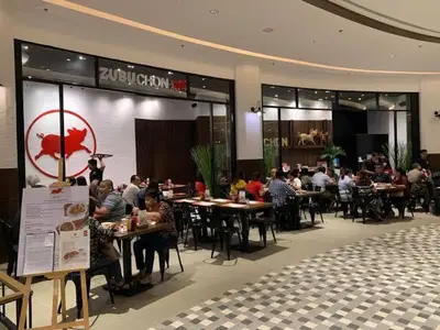 a group of people sitting at tables in a restaurant at Cozy Condo Apartment in Makati / Manila with mall, restaurants, groceries, pool, netflix, disney+ and more in Manila
