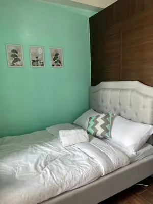 a white bed with two pillows on top of it at Cozy Condo Apartment in Makati / Manila with mall, restaurants, groceries, pool, netflix, disney+ and more in Manila