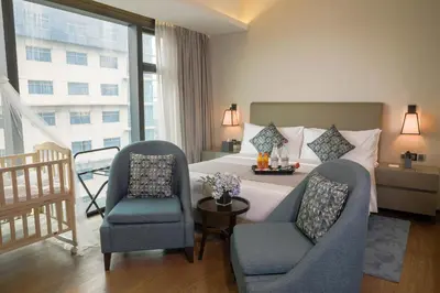 a hotel room with a bed and two chairs at Oakwood Makati Avenue in Manila