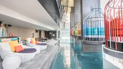 a hotel lobby with a swimming pool and chairs at Oakwood Makati Avenue in Manila