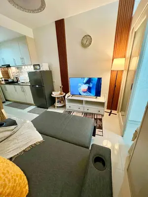 a living room with a couch and a tv at Sea Residences: Eyal’s Suite Condotel near MOA/Mall of Asia in Manila