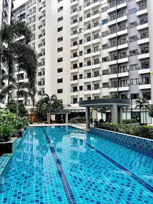 a large blue swimming pool in front of a large building at Spring Residences Affordable Condotel Bicutan Paranaque near NAIA Airport in Manila