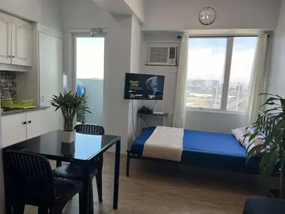 a small room with a bed and a table and a kitchen at Ultimate getaway in Alabang at Anuva Residences in Manila