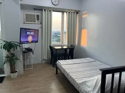 a room with a bed and a tv and a table at Ultimate getaway in Alabang at Anuva Residences in Manila