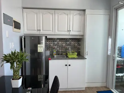 a kitchen with white cabinets and a refrigerator at Ultimate getaway in Alabang at Anuva Residences in Manila