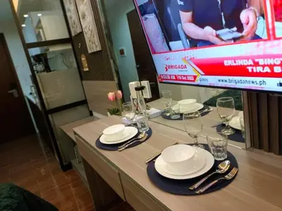 a table with plates and wine glasses on a television at Cozy Family Nook at Makati in Manila