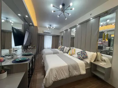 a hotel room with two beds and a television at Cozy Family Nook at Makati in Manila