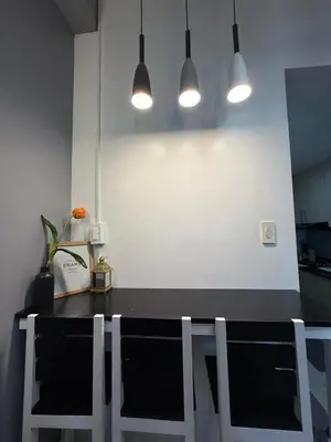a kitchen with a black counter with chairs and lights at Jamellas' Smile Home in Manila