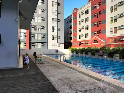 two people standing next to a pool in a building at Nathan's Staycation in Manila