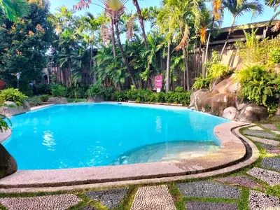 a swimming pool in a resort with palm trees at Nathan's Staycation in Manila