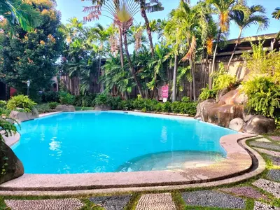 a swimming pool in a resort with palm trees at Nathan's Staycation in Manila