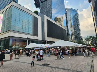a crowd of people walking in a city with tents at BGC Avant at The Fort Cosy and Vibrant 2BR near Burgos Circle in Manila