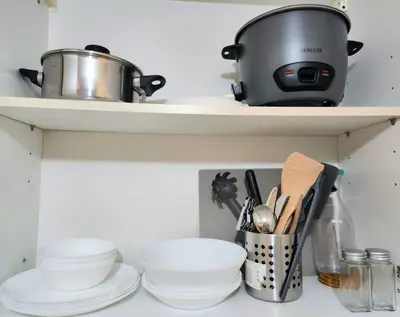 a kitchen shelf with dishes and a pot at BGC Avant at The Fort Cosy and Vibrant 2BR near Burgos Circle in Manila