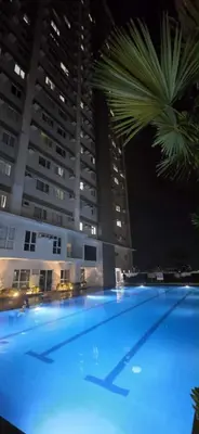 a large swimming pool at night with tall buildings at Relaxing Haven at Covent Garden in Manila