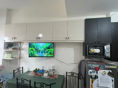 a kitchen with a table and a tv on the wall at Relaxing Haven at Covent Garden in Manila