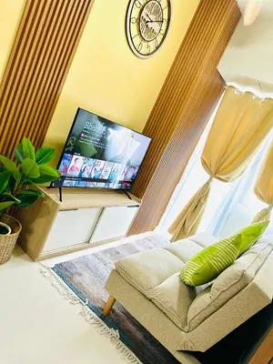 a living room with a couch and a clock on the wall at Chic and Cozy 1BR Shore 3 by SMDC near MOA in Manila