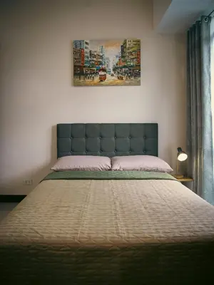 a bedroom with a large bed with a blue headboard at The Bat Cave 2 at Manhattan Heights Araneta Cubao in Manila