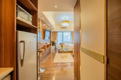 a kitchen with a refrigerator and a living room at House of Tulips in Air Residences Makati City in Manila