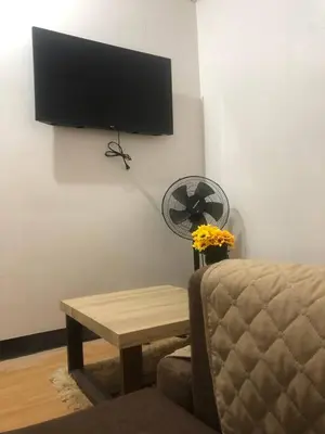 a living room with a chair and a table and a tv at Amenadiel & CC - Imus Staycation in Imus