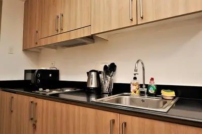 a kitchen with a stainless steel sink and wooden cabinets at STAR CITY 1148 DYNASTEL SHORE Staycation in Manila
