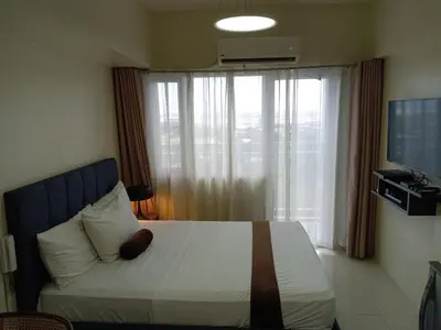 a bedroom with a bed with a large window at Studio unit at The Breeze Residence in Manila