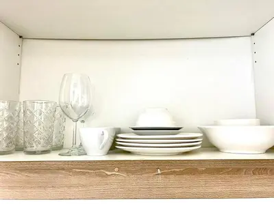 a shelf with plates and bowls and a wine glass at DFA ASEANA 1158 DYNASTEL SHORE Staycation in Manila